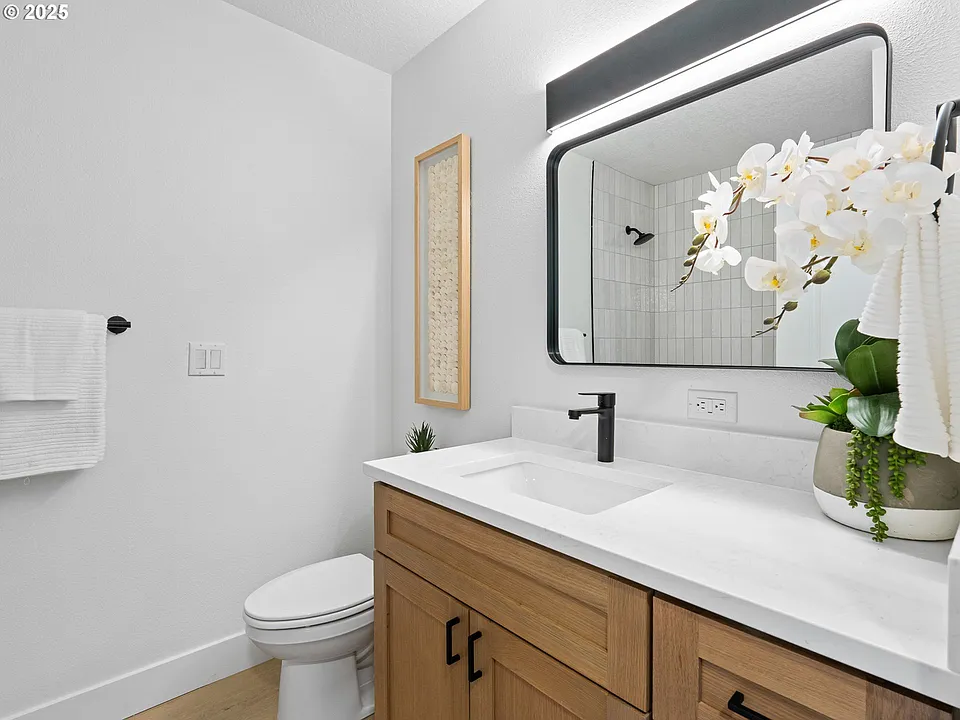 Updated bathroom with wood vanity, quartz top, and tiled shower