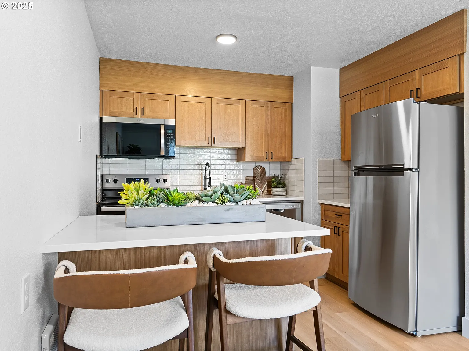 Updated kitchen with island seating, oak cabinets, and stainless appliances